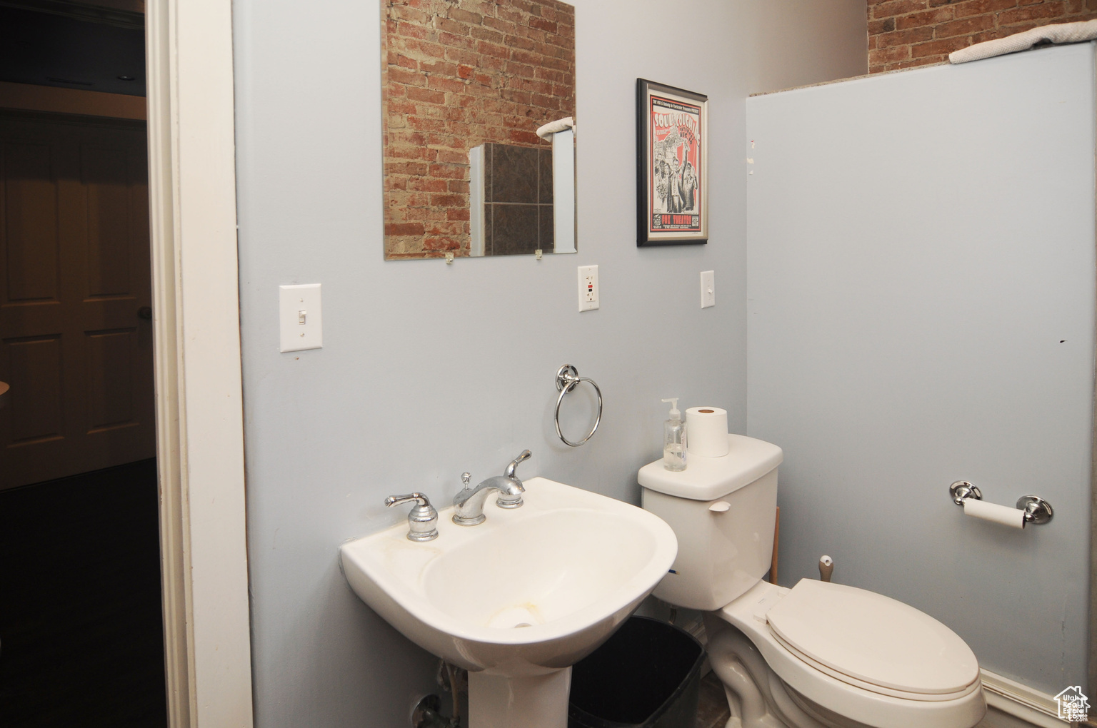 Bathroom featuring brick wall, sink, and toilet