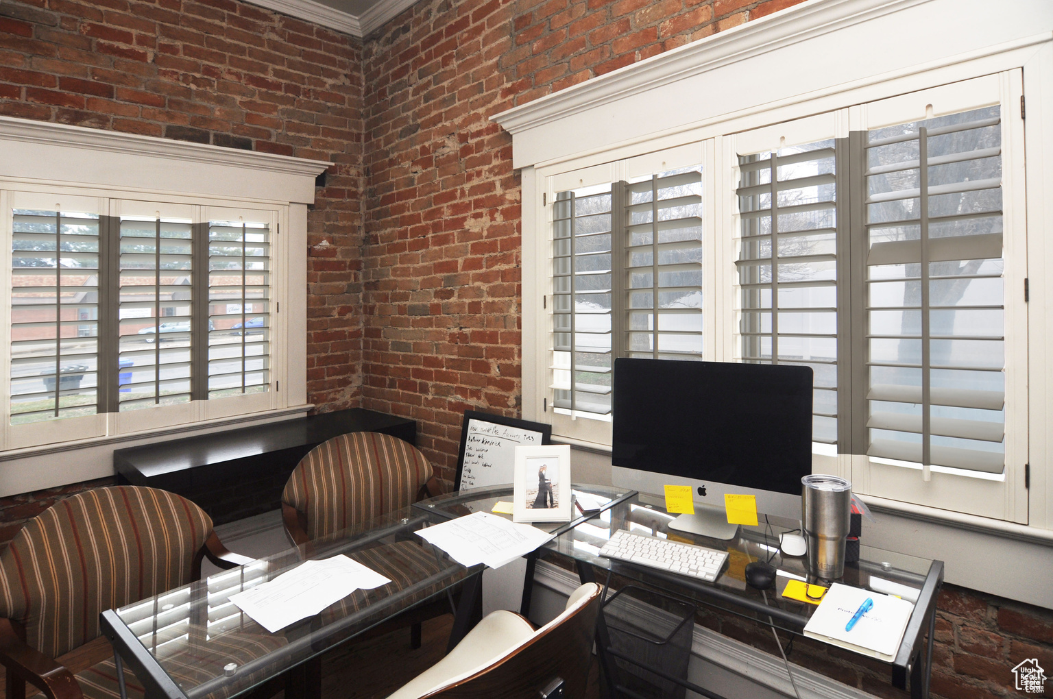 Office with ornamental molding and brick wall