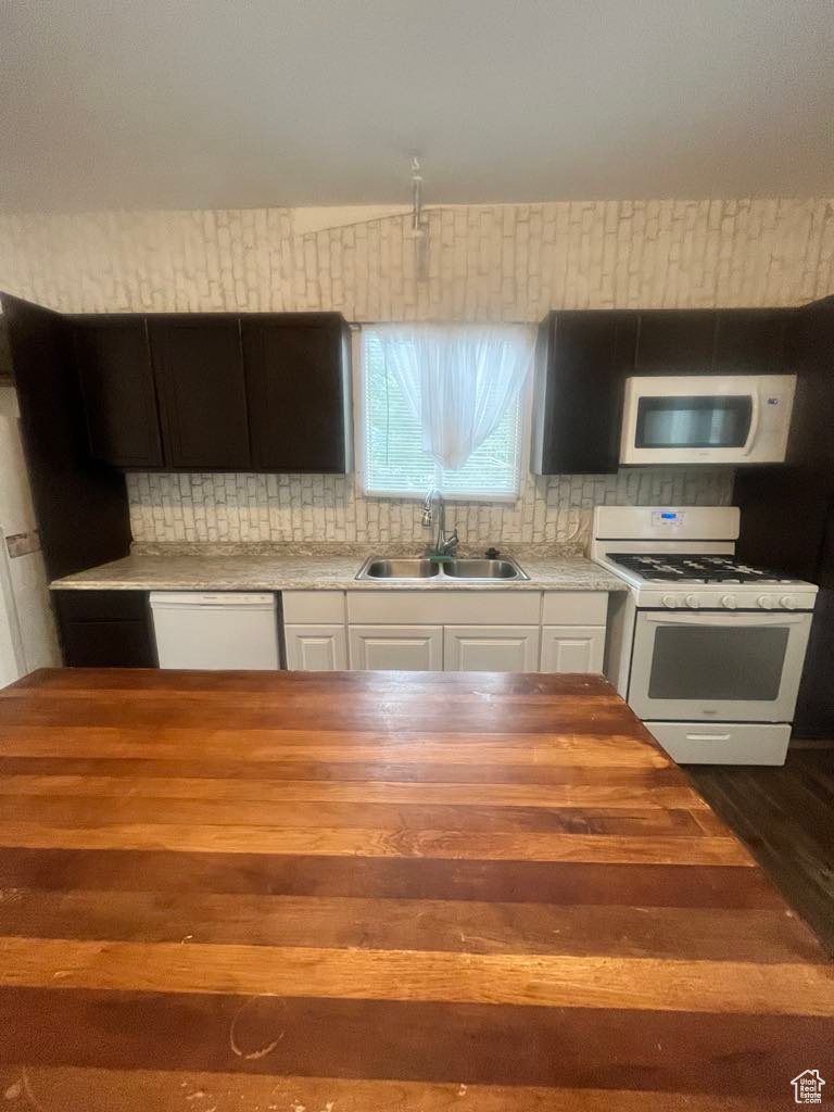 Kitchen featuring white appliances, sink, decorative backsplash, dark hardwood / wood-style floors, and white cabinetry