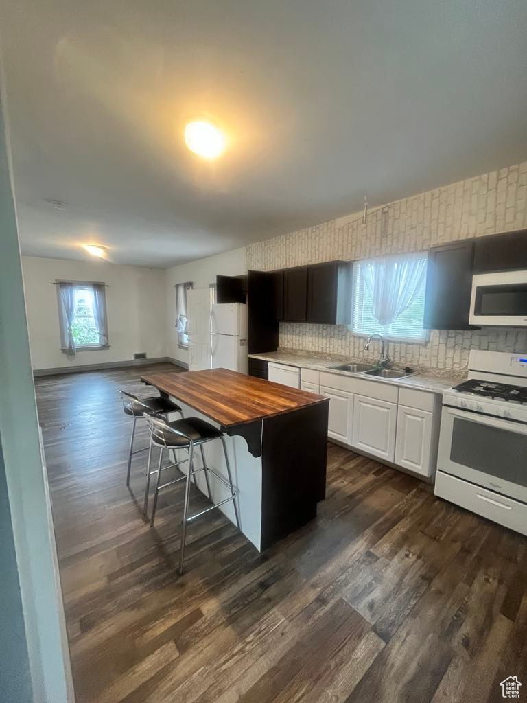 Kitchen featuring dark hardwood / wood-style floors, white appliances, sink, white cabinetry, and wood counters