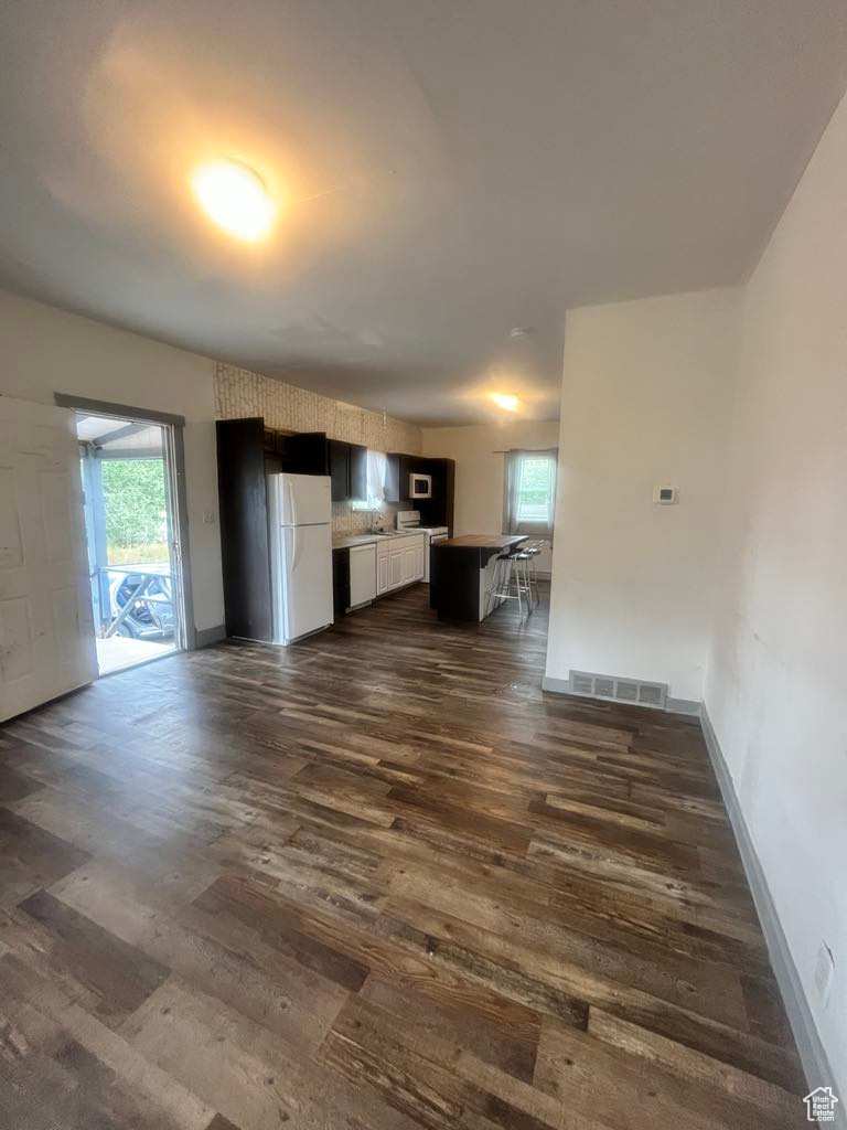 Unfurnished living room featuring dark wood-type flooring