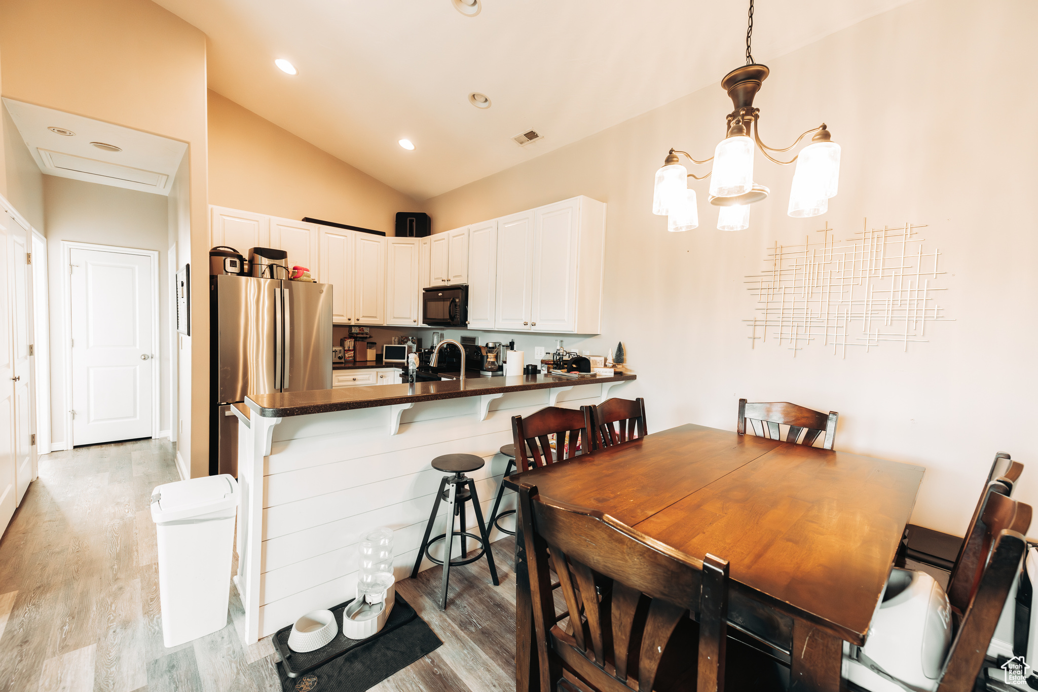 Dining space with lofted ceiling, light hardwood / wood-style floors, a chandelier, and sink