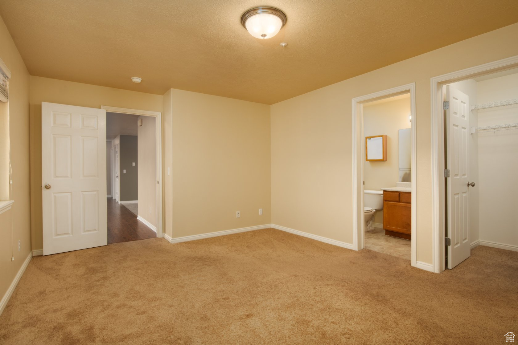 Unfurnished bedroom featuring a closet, a walk in closet, carpet, and ensuite bath