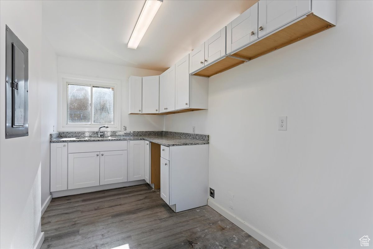 Kitchen with electric panel, dark hardwood / wood-style floors, and white cabinetry