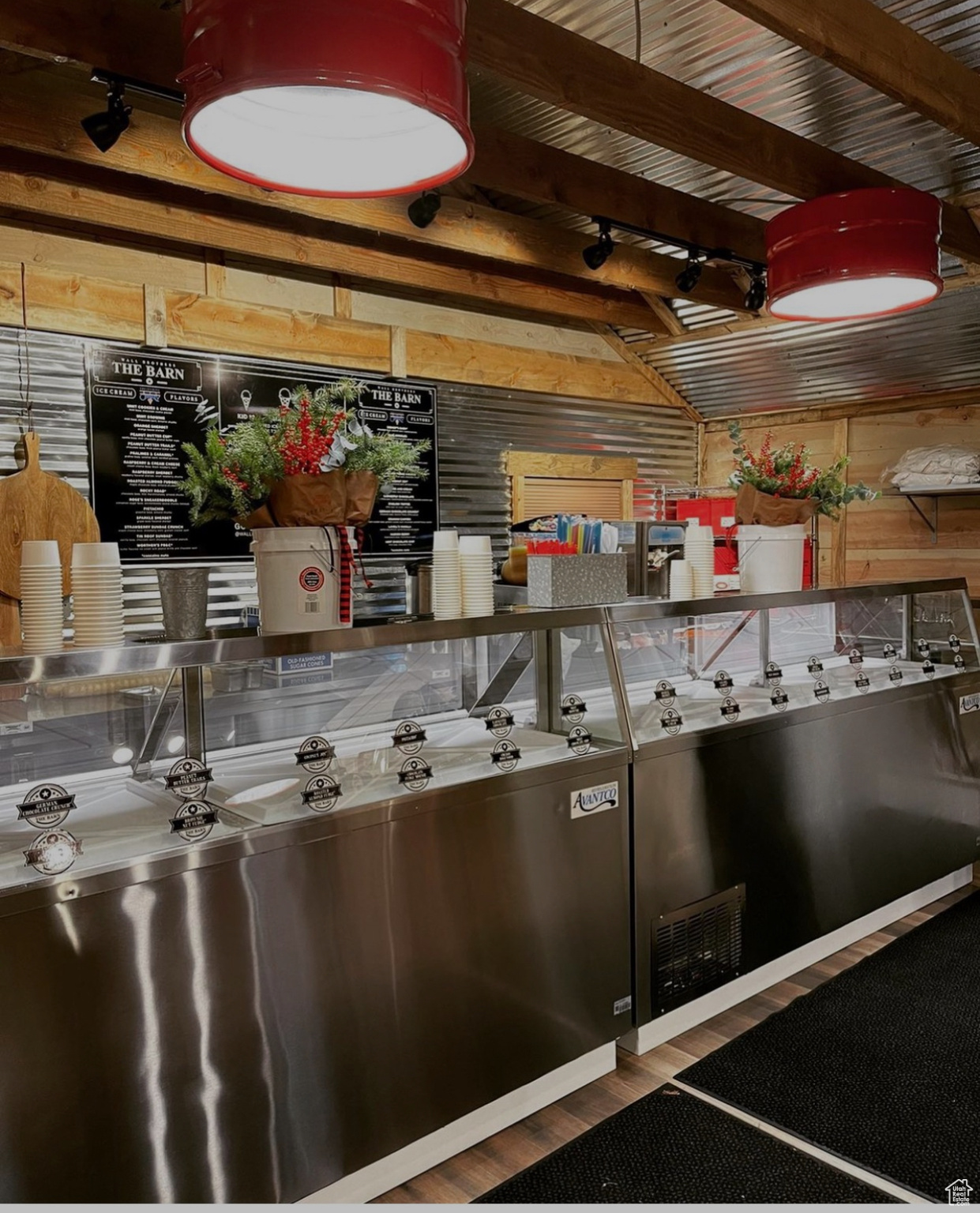 Kitchen featuring beam ceiling, wooden walls, stainless steel counters, and hardwood / wood-style flooring