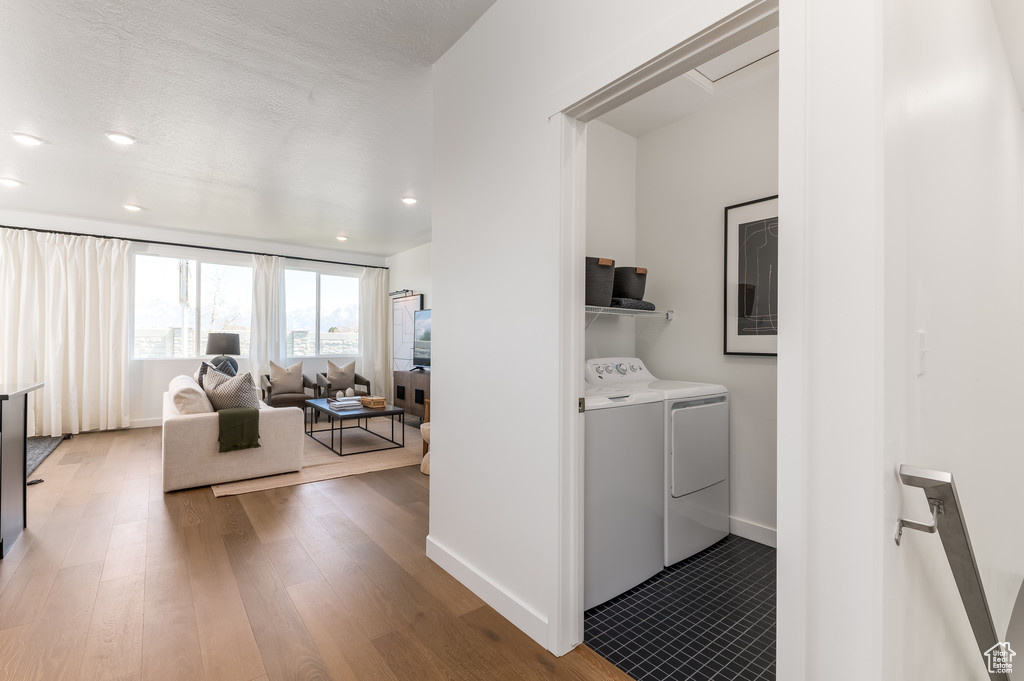 Washroom featuring wood-type flooring, a textured ceiling, and washing machine and clothes dryer