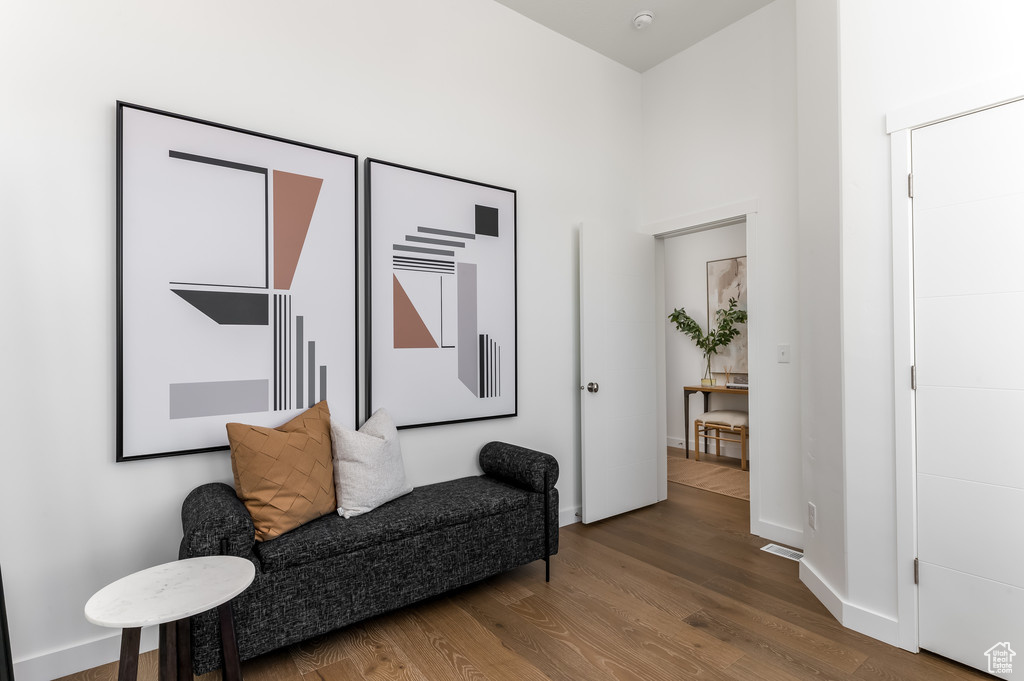 Sitting room with a towering ceiling and hardwood / wood-style flooring