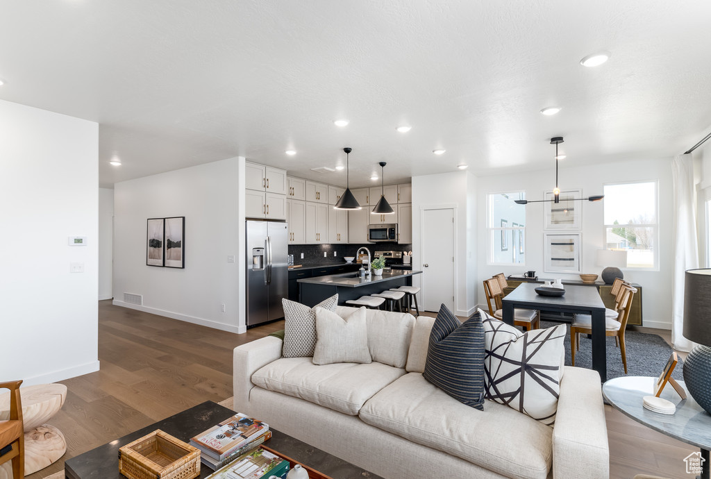 Living room with hardwood / wood-style flooring, sink, and an inviting chandelier