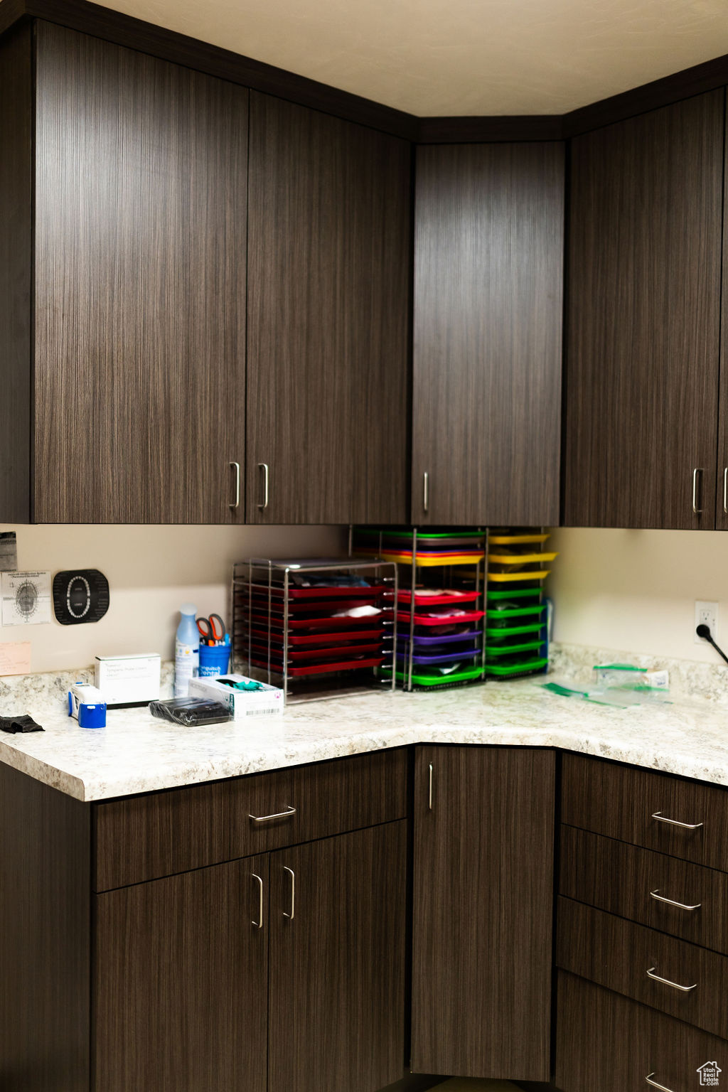 Kitchen featuring light stone counters and dark brown cabinets