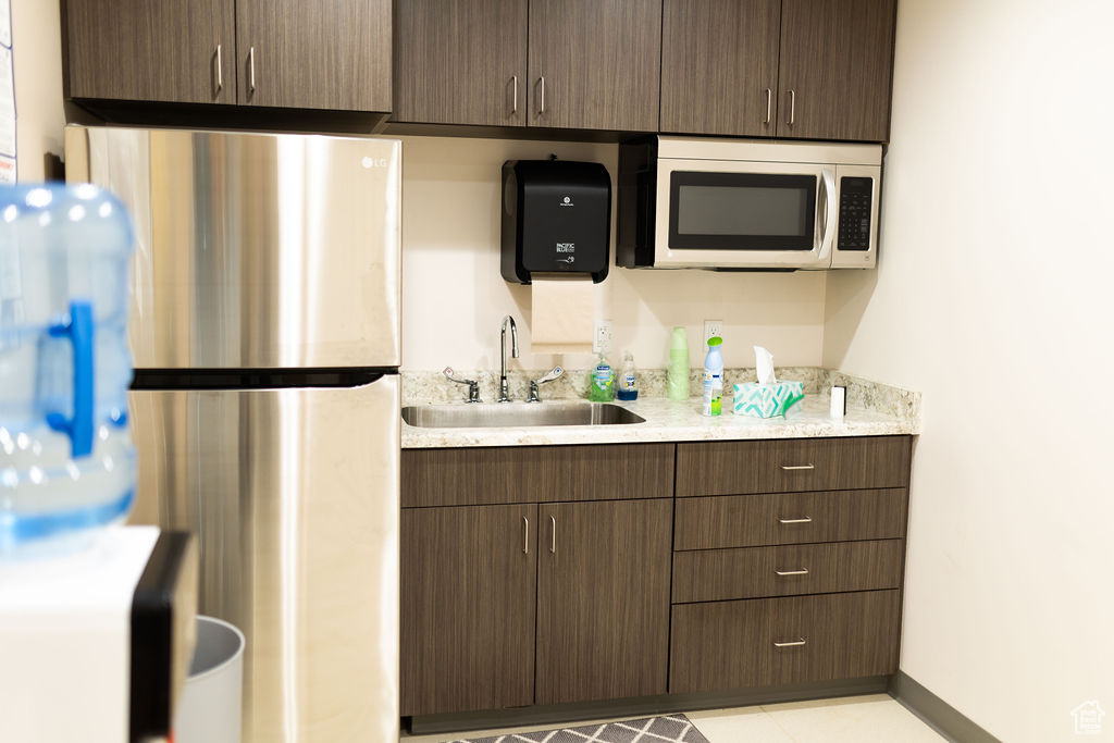 Kitchen with stainless steel fridge, sink, and dark brown cabinets