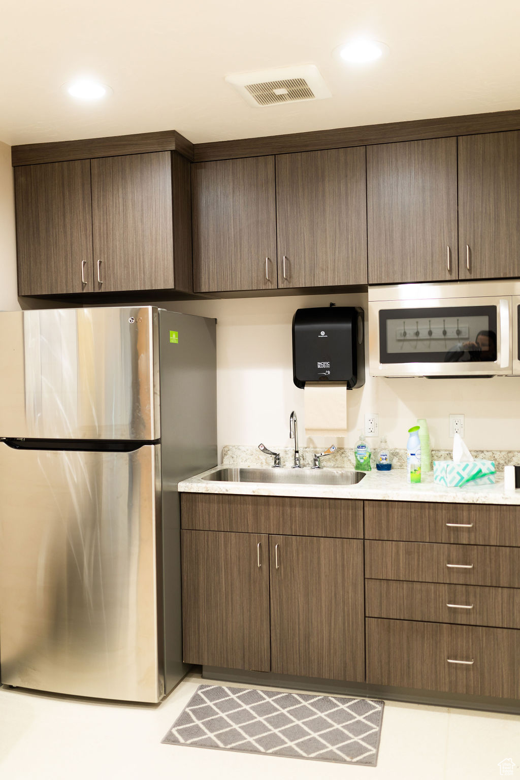 Kitchen with stainless steel appliances, dark brown cabinetry, and sink