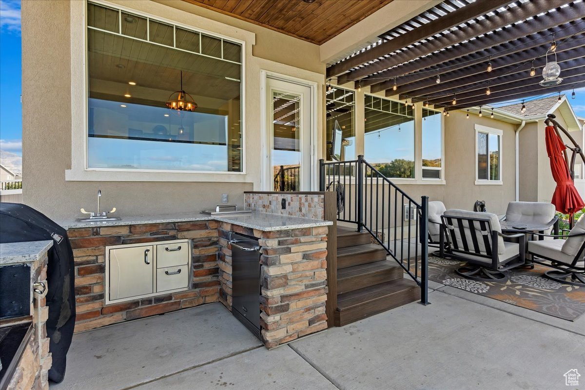 View of patio featuring grilling area, sink, an outdoor kitchen, and a pergola