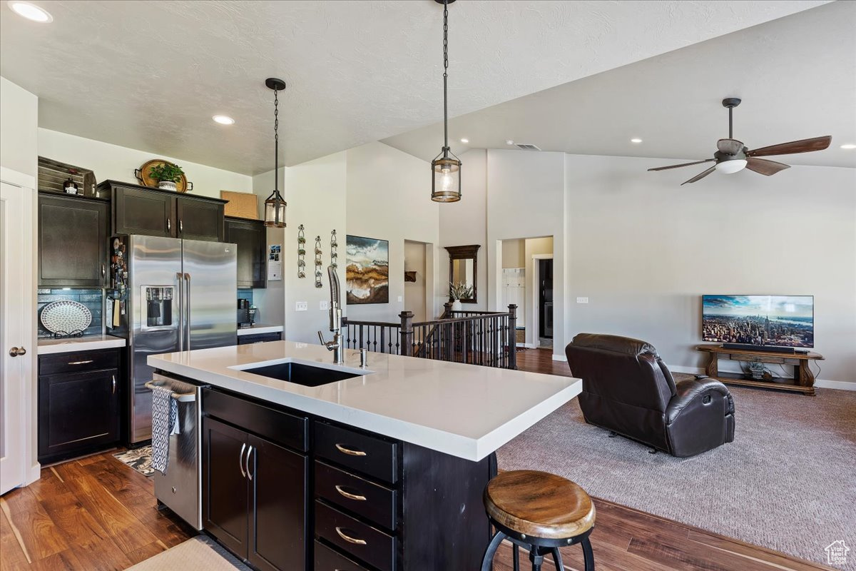 Kitchen featuring decorative light fixtures, a center island with sink, sink, and dark hardwood / wood-style flooring