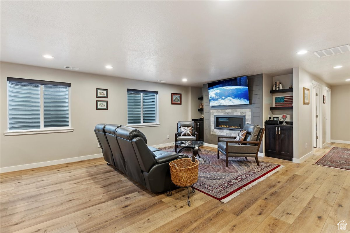 Living room with light hardwood / wood-style floors and a large fireplace