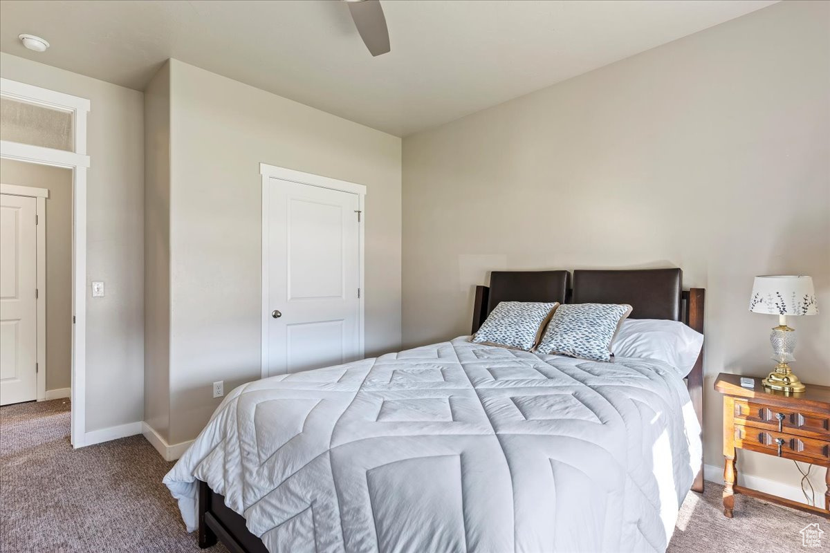 Carpeted bedroom featuring ceiling fan