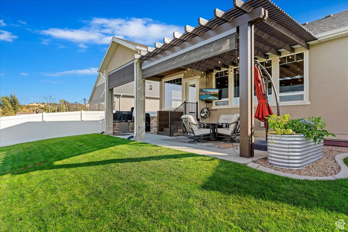 Back of house with a pergola, a patio area, and a lawn