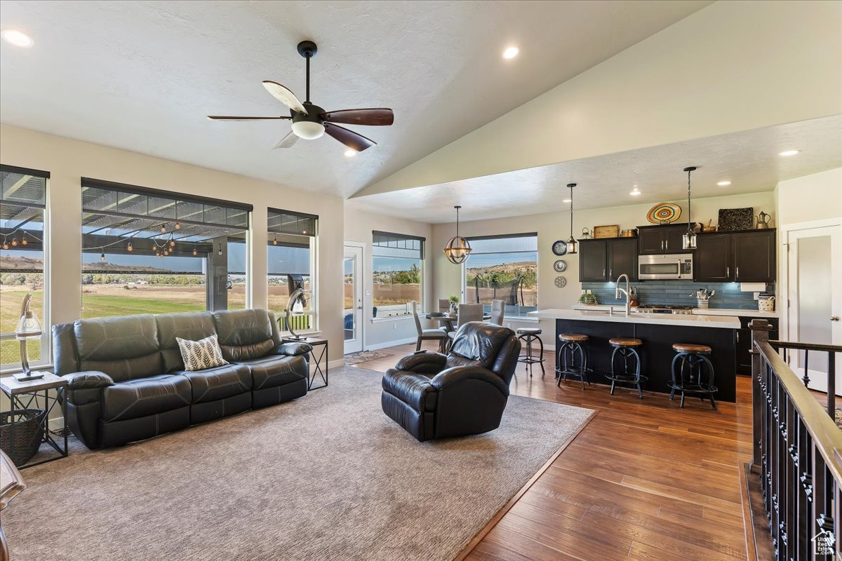 Living room with dark hardwood / wood-style floors, high vaulted ceiling, sink, and ceiling fan