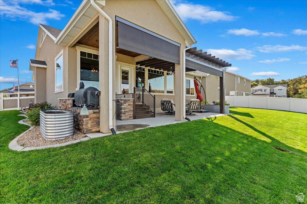 Rear view of house featuring a yard, a pergola, and a patio