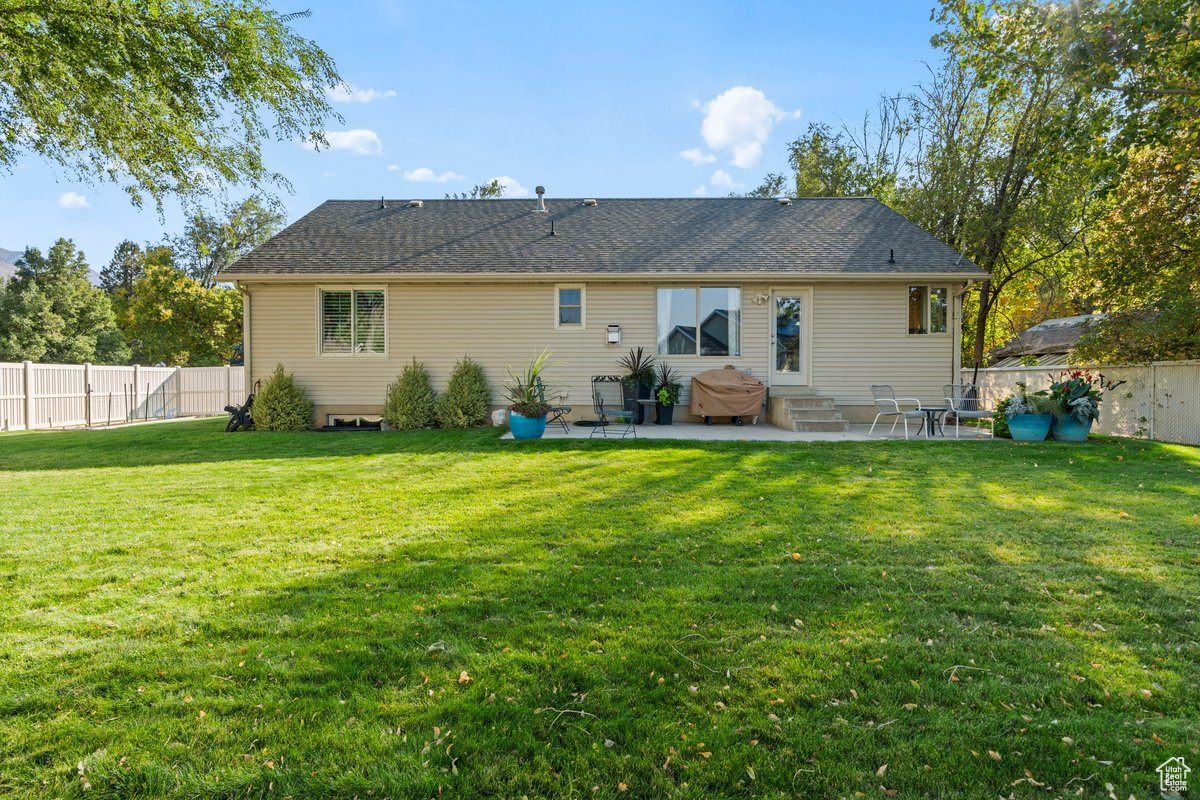 Back of property with a lawn and a patio area