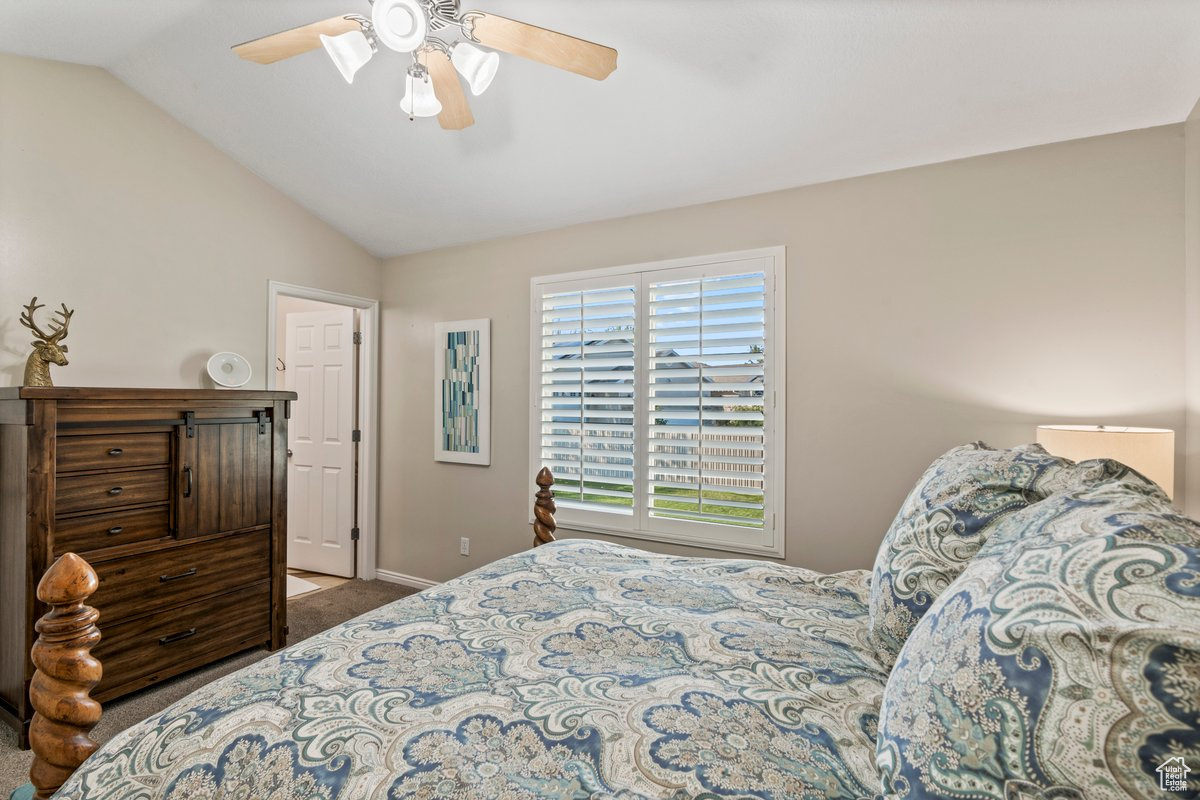 Carpeted bedroom featuring lofted ceiling and ceiling fan