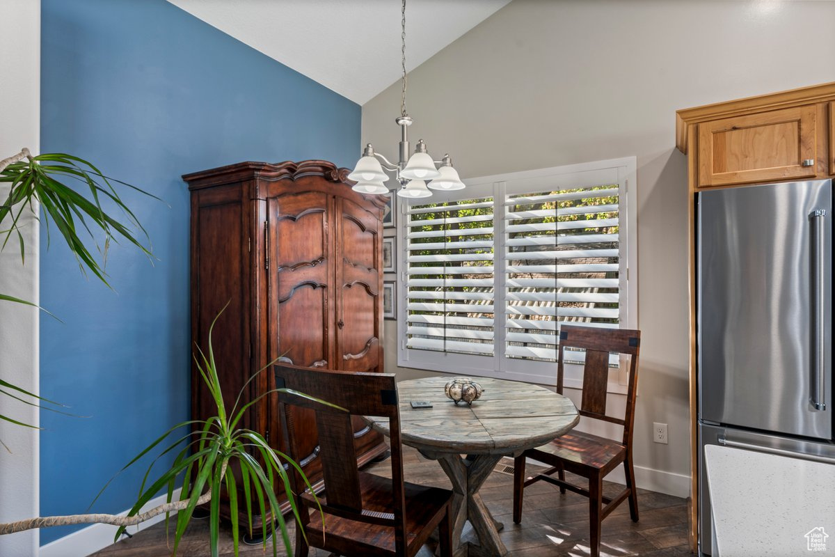 Dining space featuring a notable chandelier and high vaulted ceiling