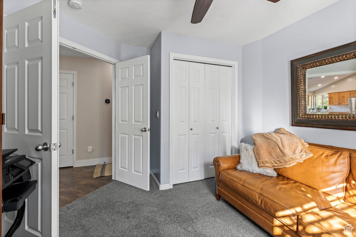 Sitting room featuring vaulted ceiling, dark carpet, and ceiling fan