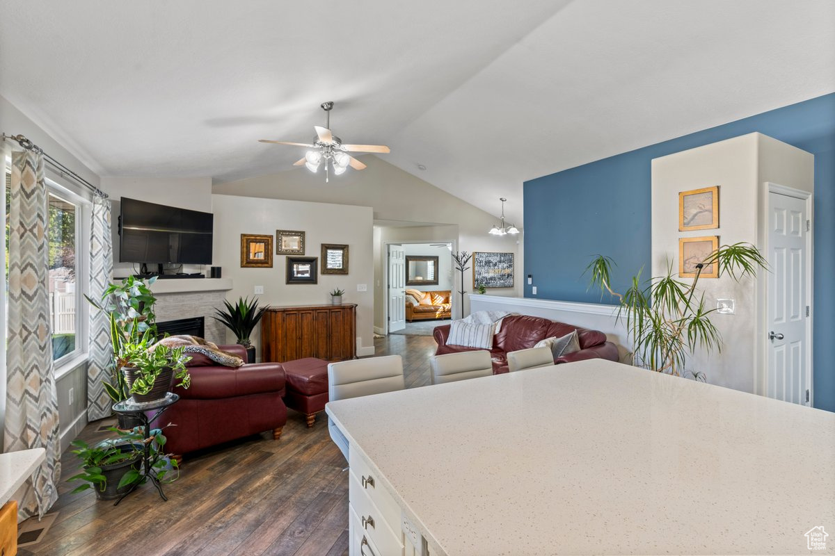 Kitchen with ceiling fan with notable chandelier, lofted ceiling, dark wood-type flooring, and white cabinets