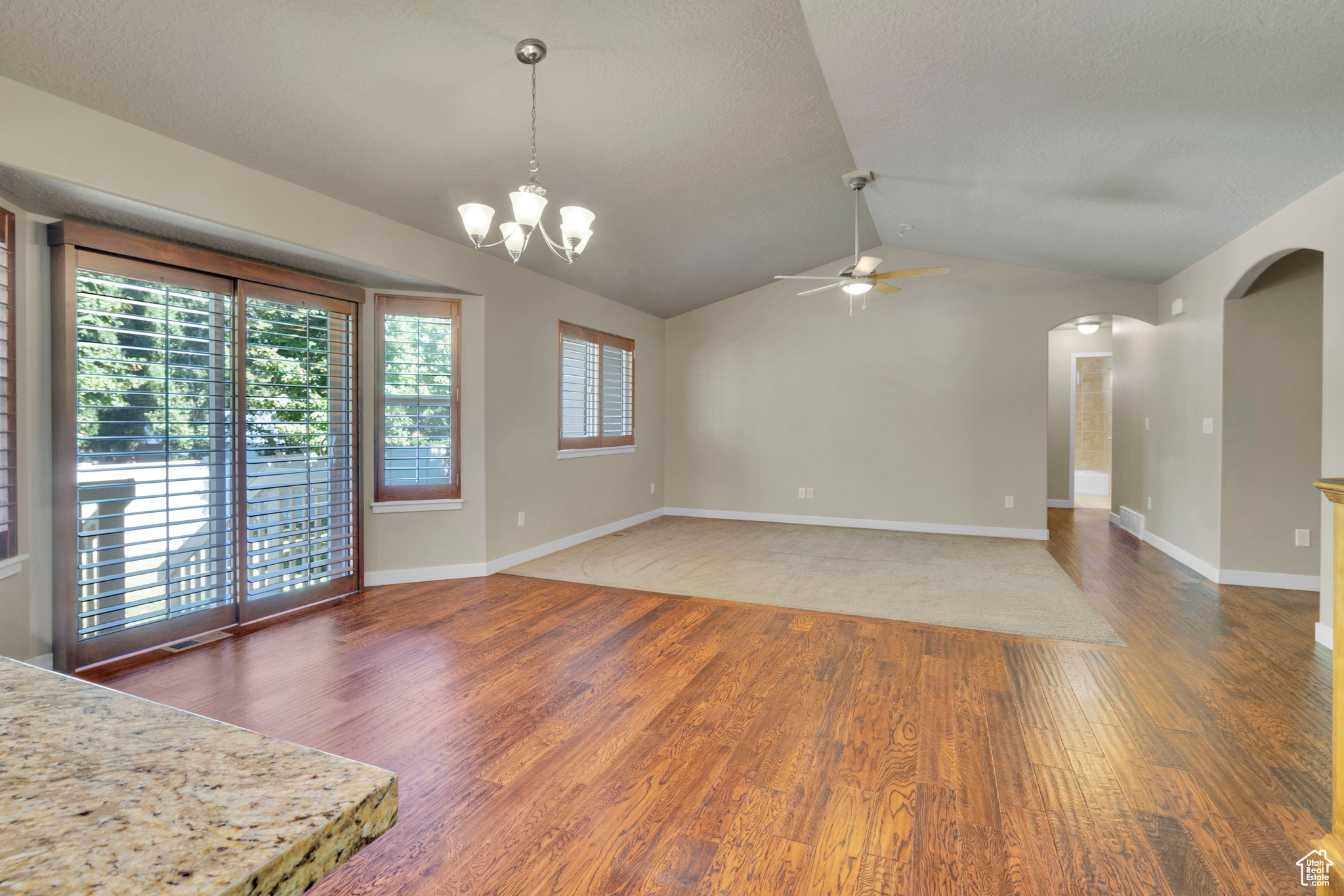 Interior space featuring dark hardwood / wood-style flooring, a textured ceiling, ceiling fan with  and vaulted ceiling