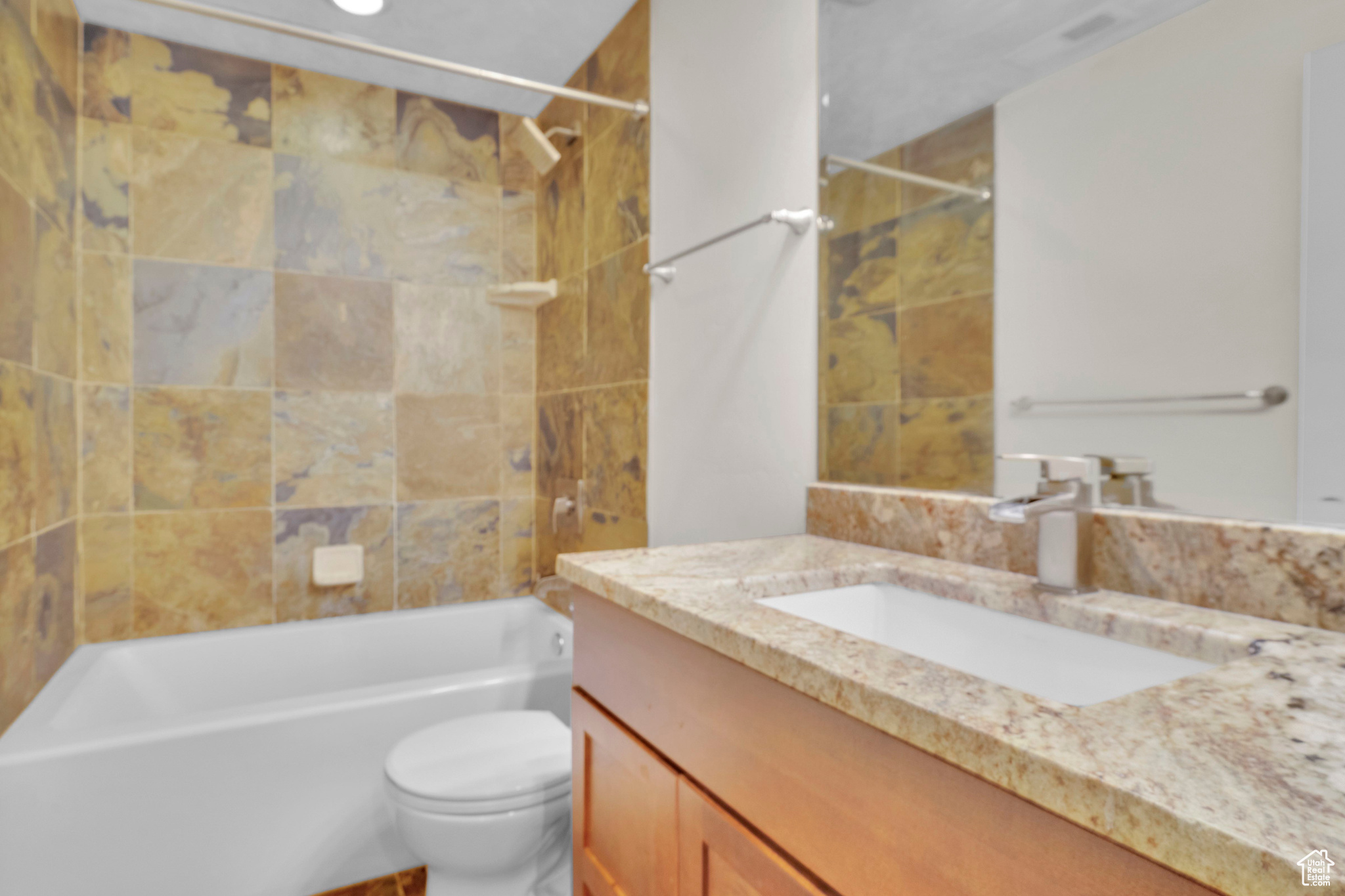 Full bathroom featuring tiled shower / bath, vanity, and toilet