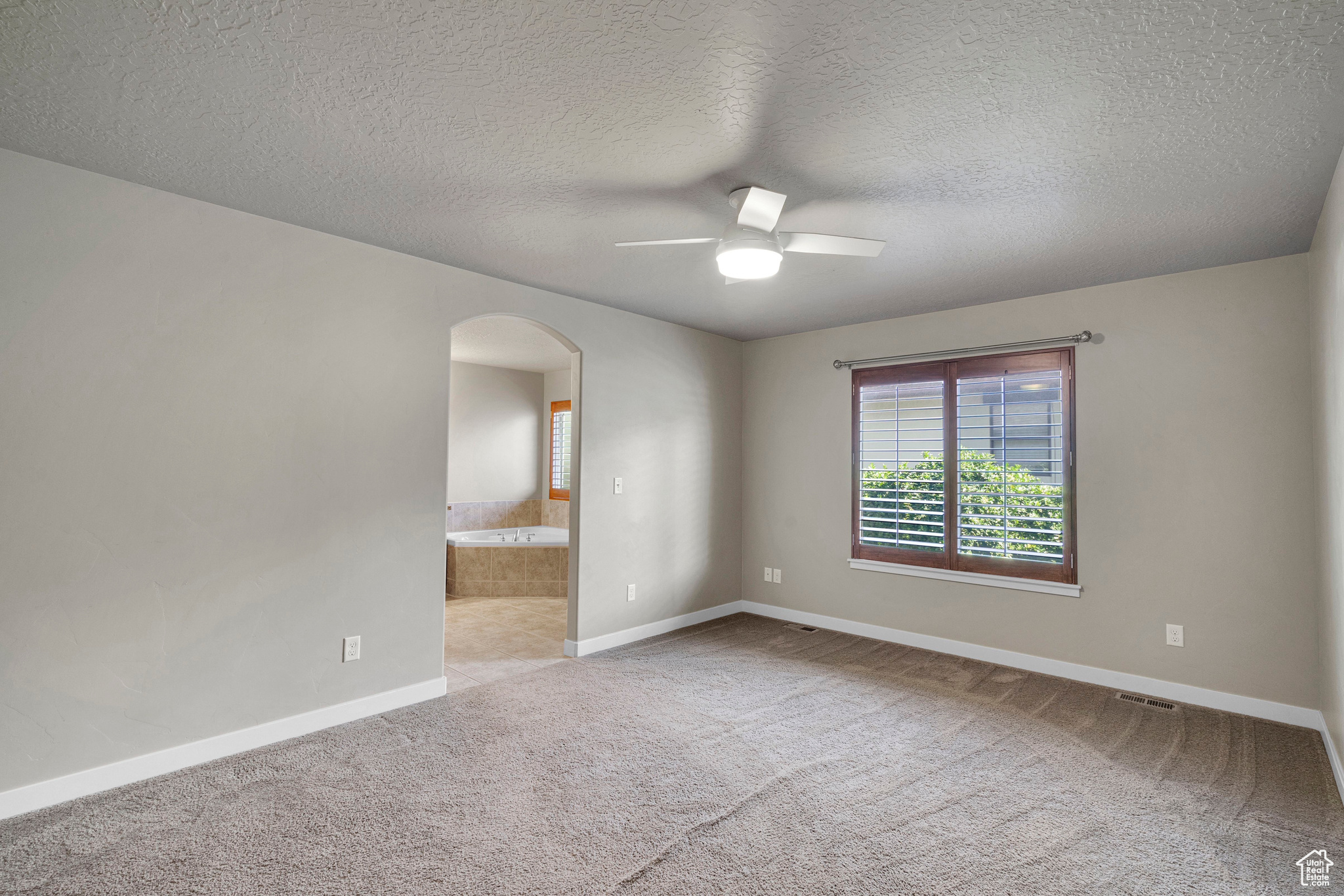 Master Bedroom featuring a textured ceiling, light colored carpet, and ceiling fan