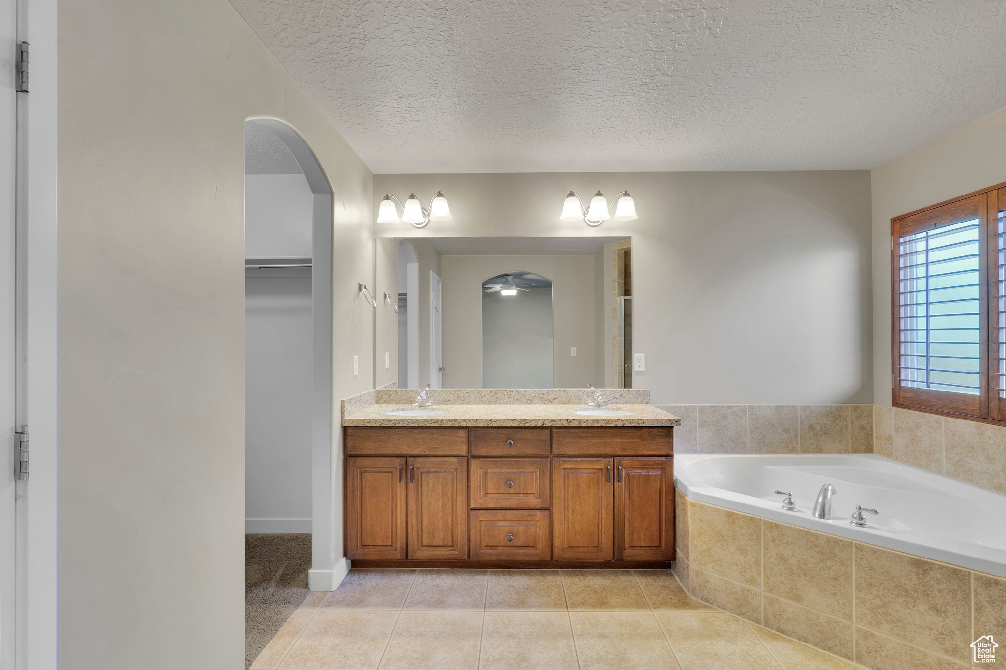 Master Bathroom with vanity, a textured ceiling, tiled bath, and tile patterned flooring