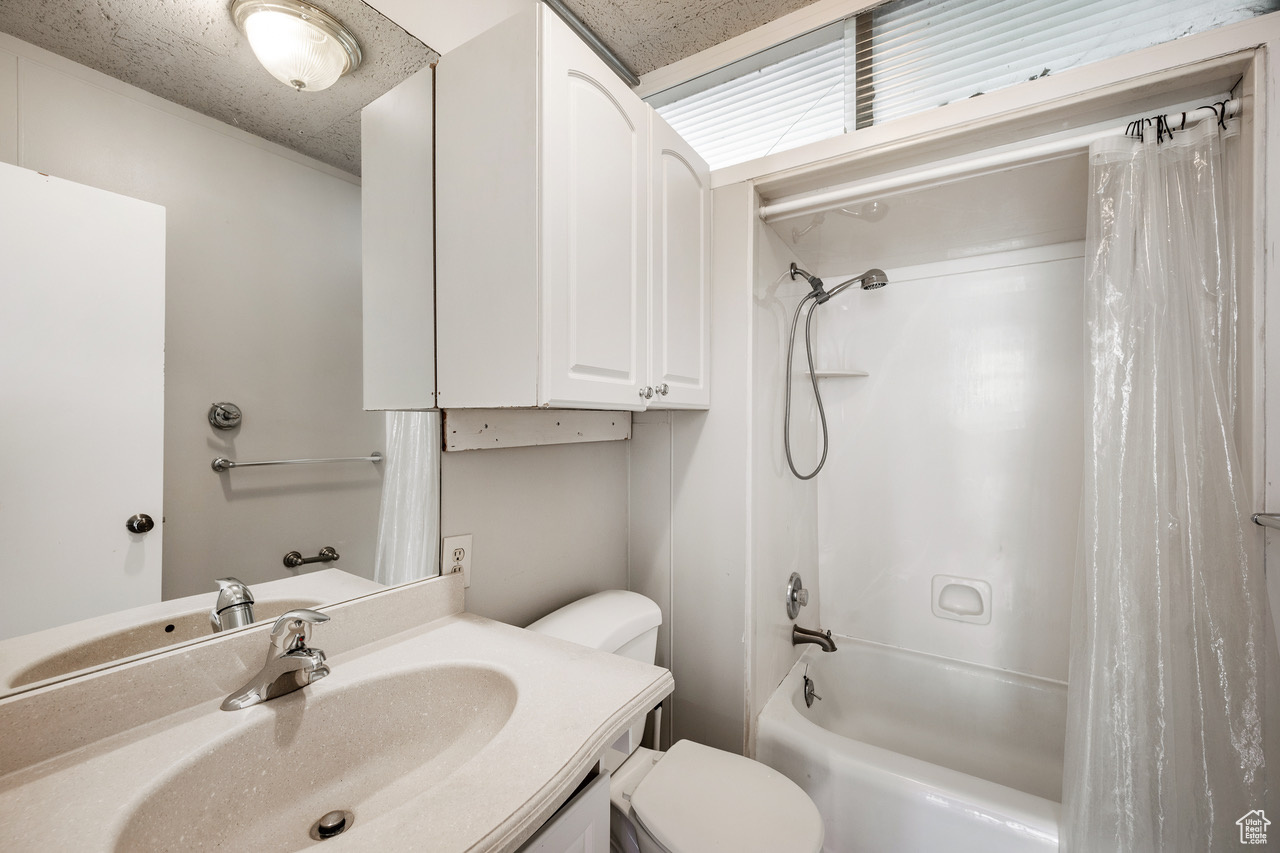 Full bathroom with vanity, shower / bath combo with shower curtain, and toilet