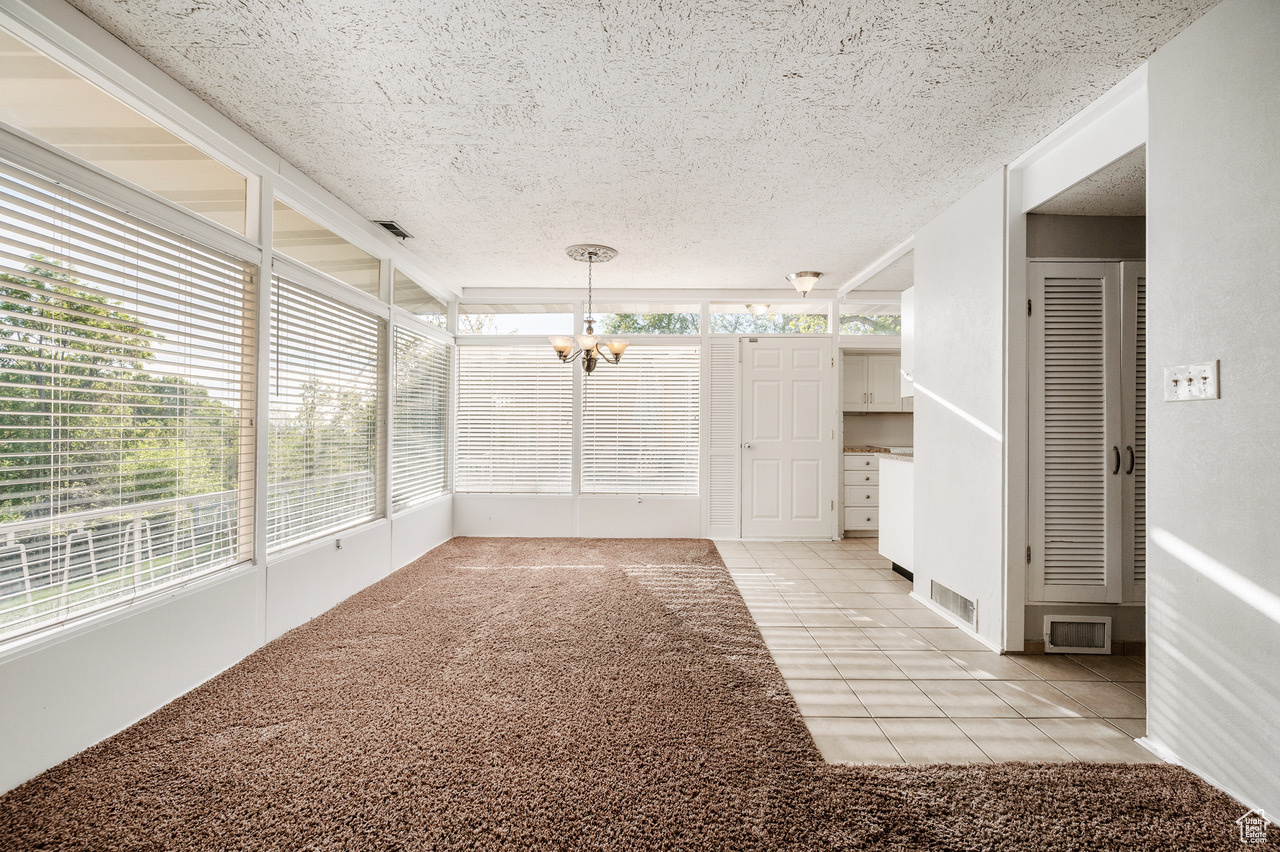 Unfurnished sunroom featuring a notable chandelier