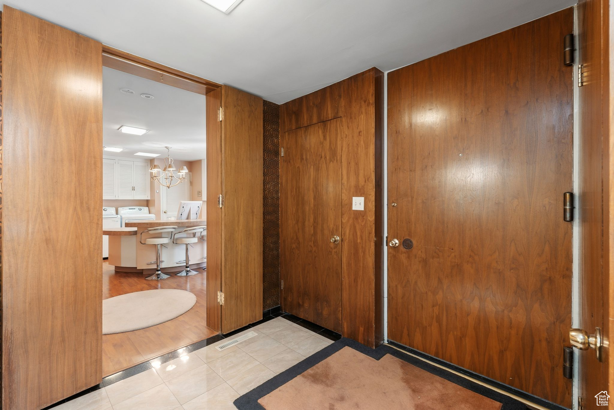 Tiled entrance foyer with walnut walls , an inviting chandelier.