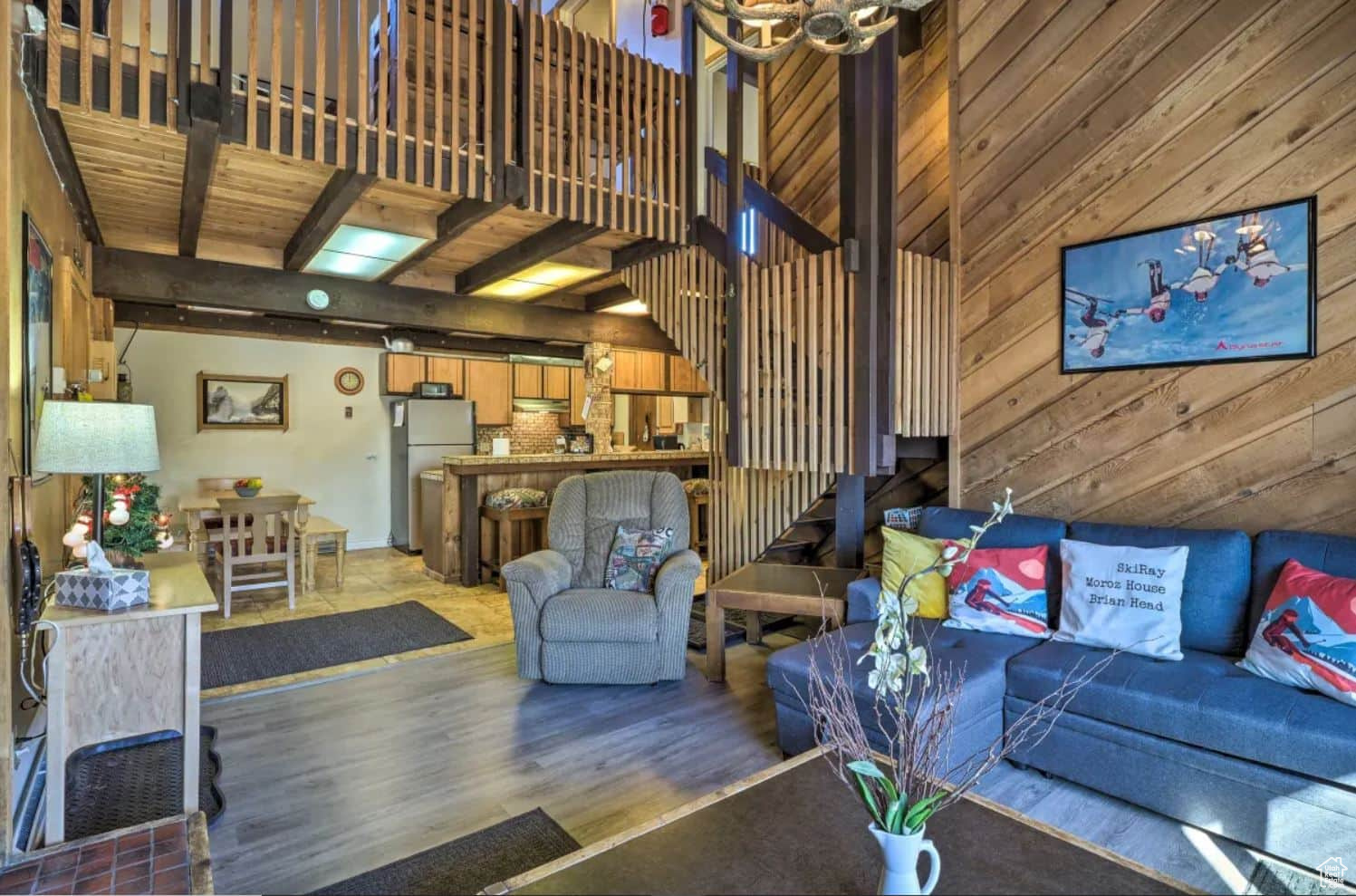 Living room featuring wood ceiling, wood walls, beam ceiling, a towering ceiling, and light hardwood / wood-style floors