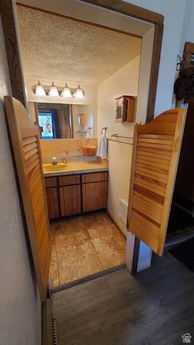 Bathroom featuring hardwood / wood-style floors, vanity, and a textured ceiling