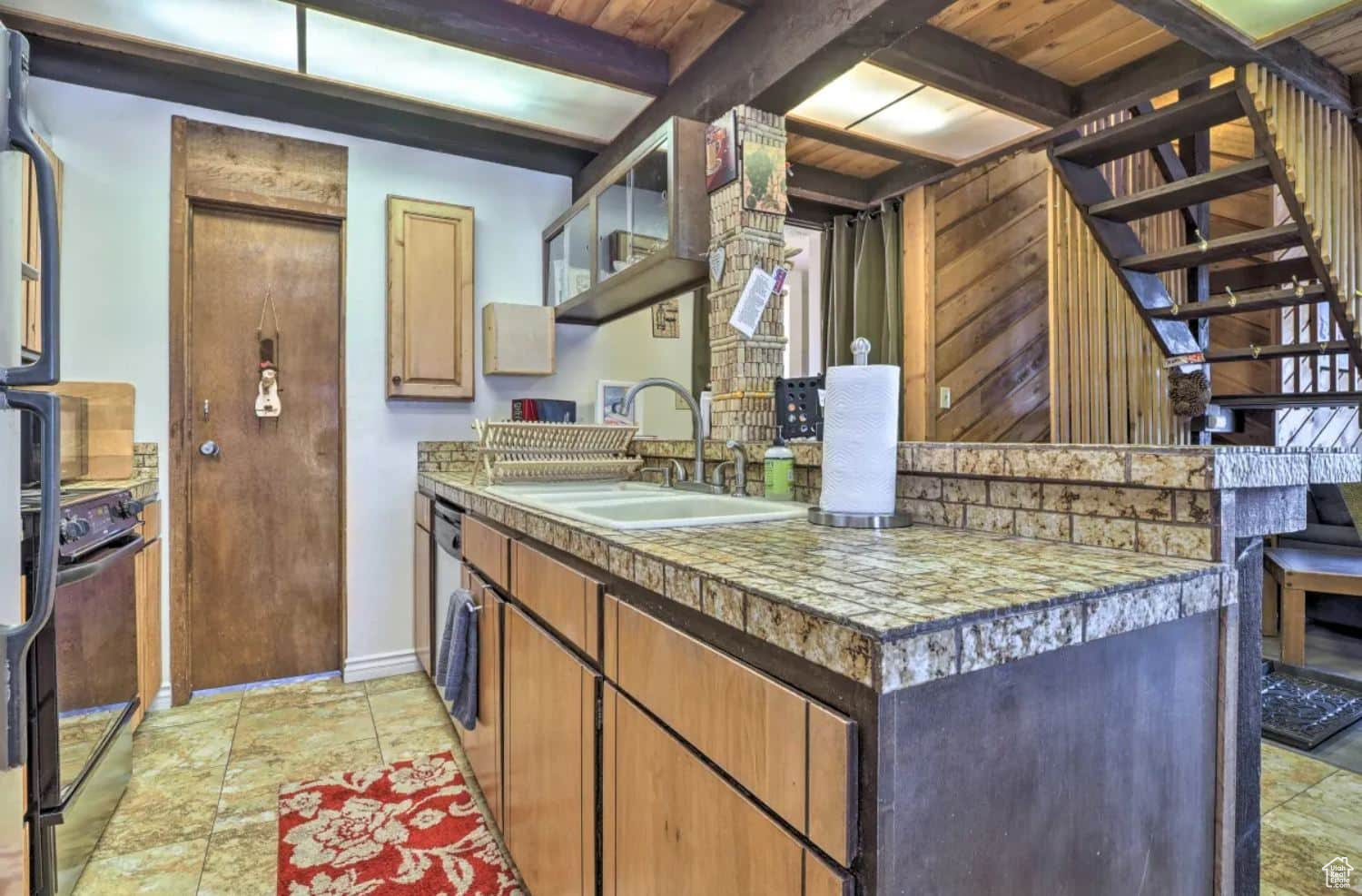 Kitchen featuring beamed ceiling, black electric range oven, sink, and wood ceiling