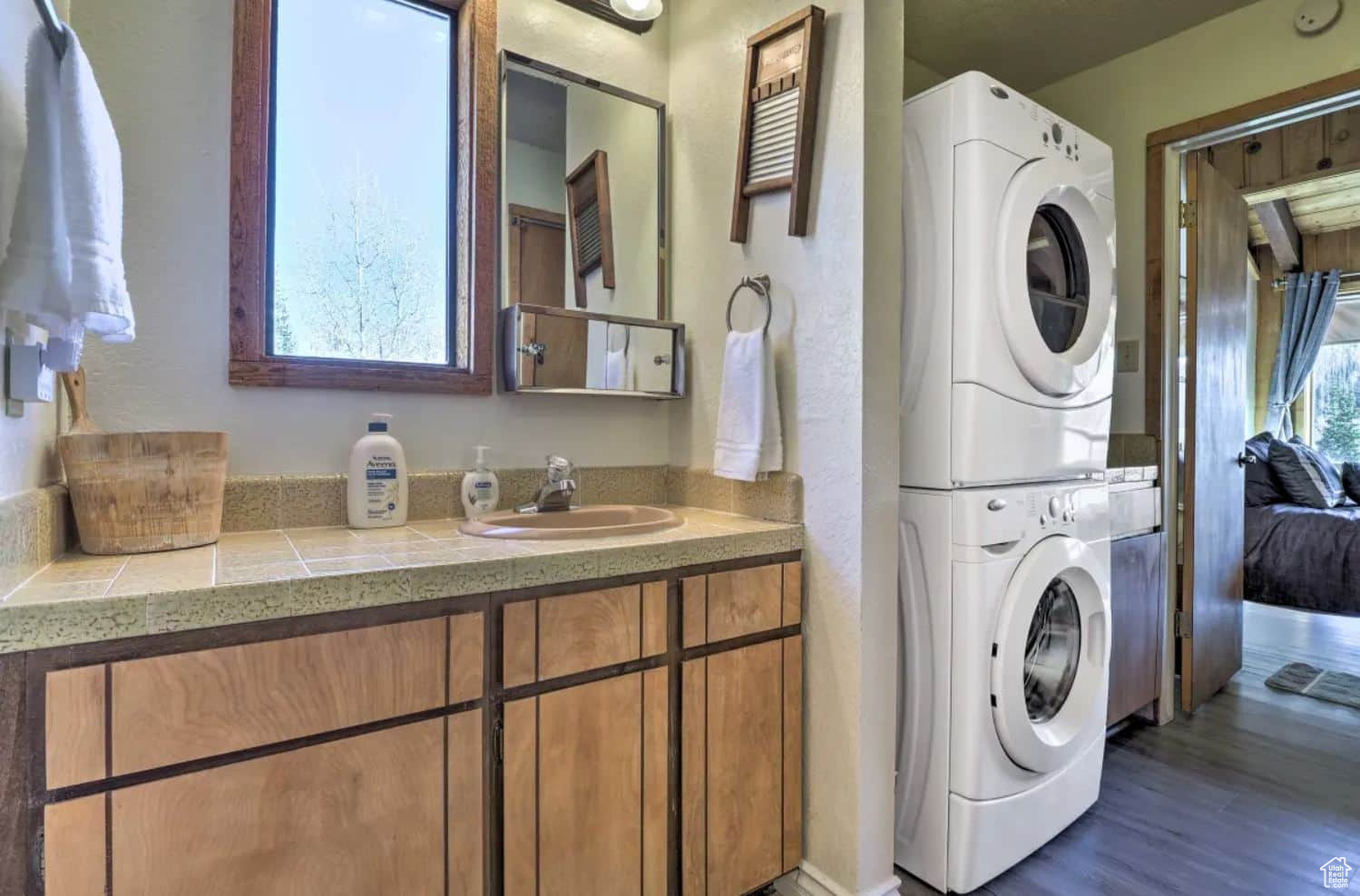 Laundry room with dark wood-type flooring, sink, and stacked washer / drying machine