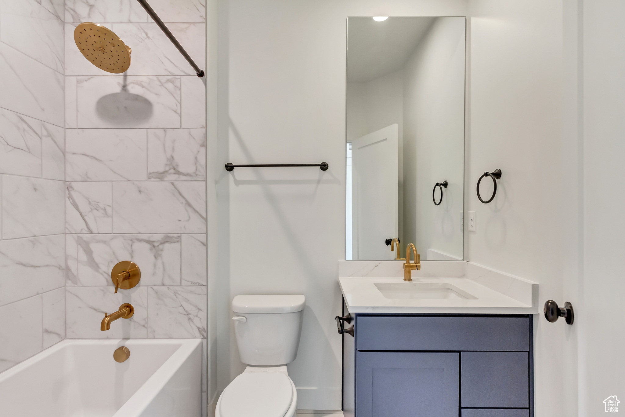 Full bathroom featuring vanity, tiled shower / bath combo, and toilet