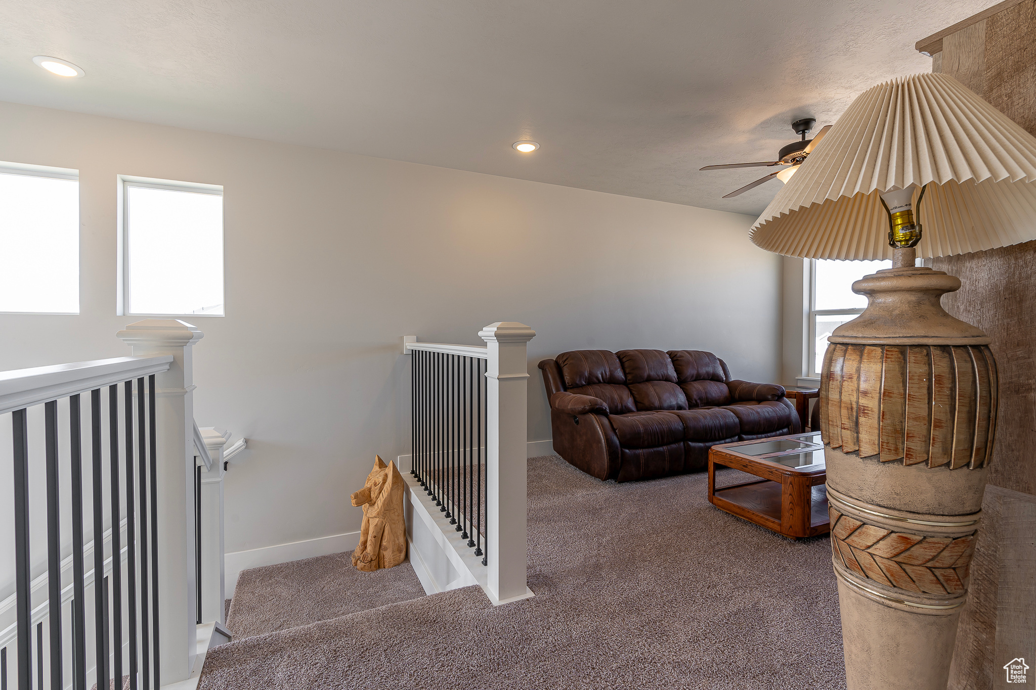 Carpeted living room with ceiling fan and plenty of natural light