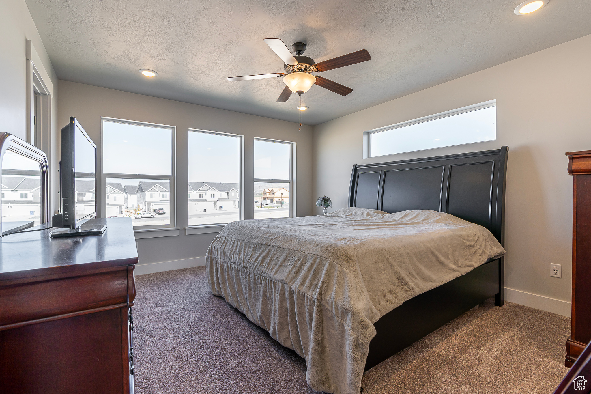 Carpeted bedroom with a textured ceiling and ceiling fan