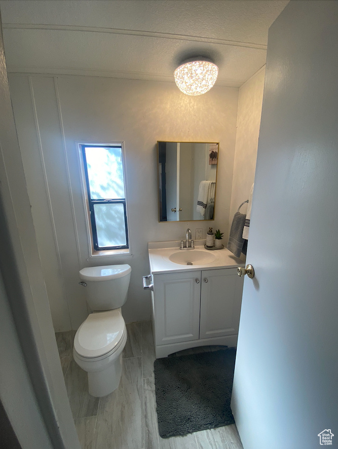 Bathroom featuring a notable chandelier, vanity, and toilet