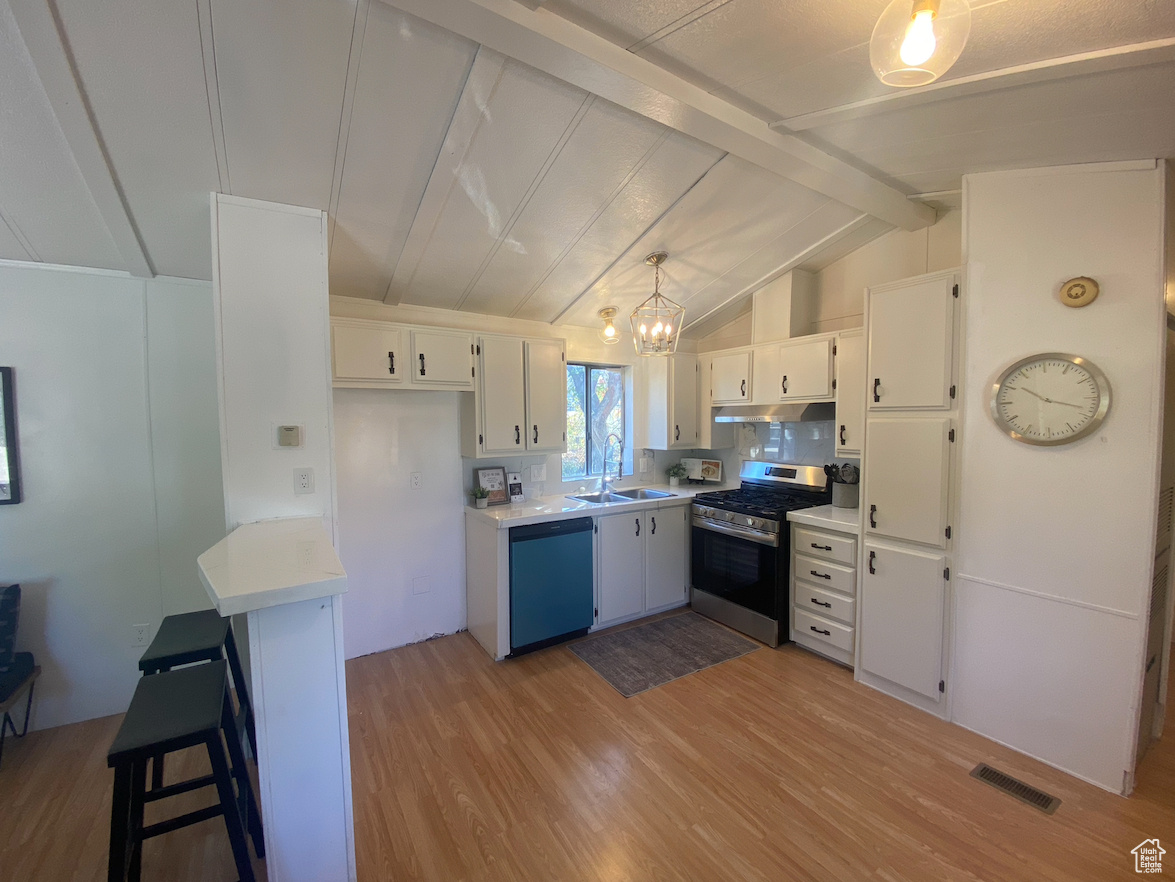 Kitchen featuring lofted ceiling with beams, light hardwood / wood-style floors, white cabinetry, appliances with stainless steel finishes, and decorative light fixtures