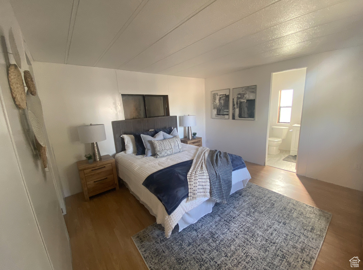 Bedroom with light hardwood / wood-style flooring and connected bathroom