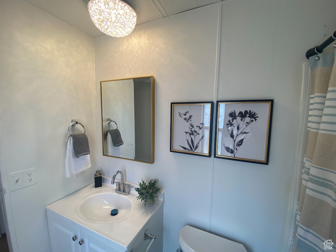 Bathroom with vanity, toilet, a chandelier, and a shower with curtain