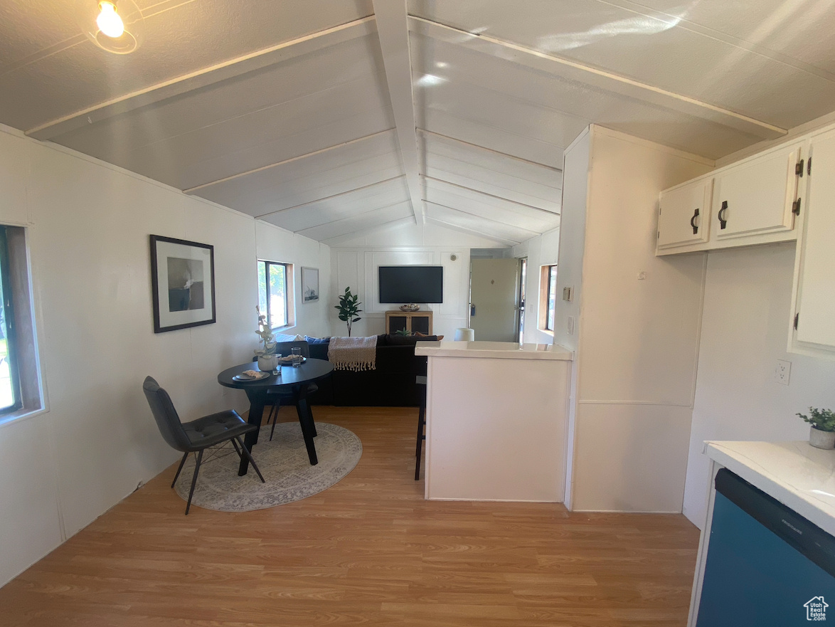 Kitchen with vaulted ceiling with beams, light wood-type flooring, and white cabinetry