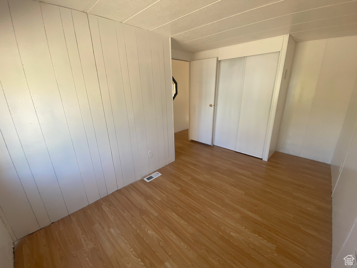 Unfurnished bedroom with wood walls, a closet, and hardwood / wood-style floors