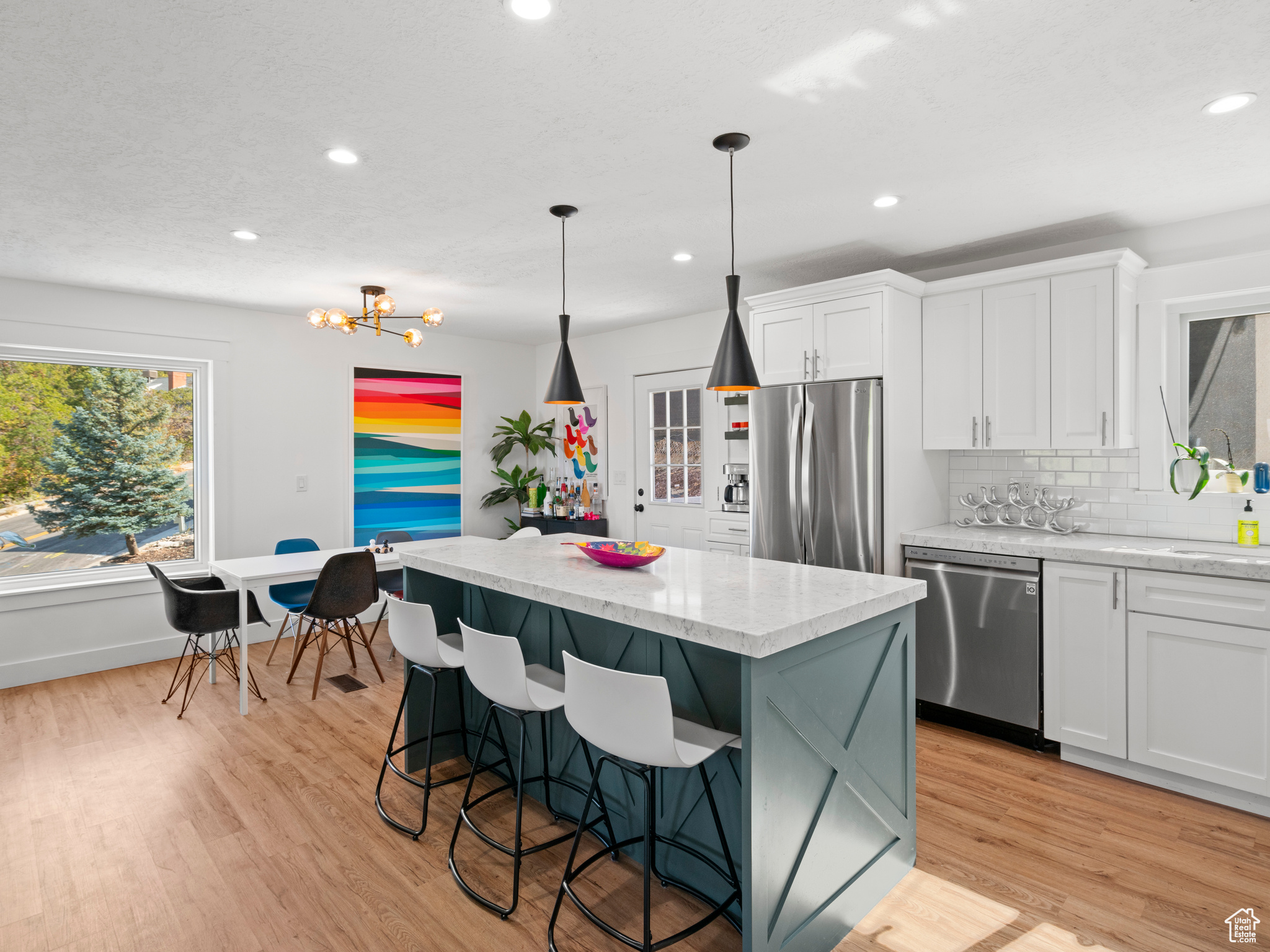 Kitchen featuring a center island, appliances with stainless steel finishes, pendant lighting, and white cabinetry