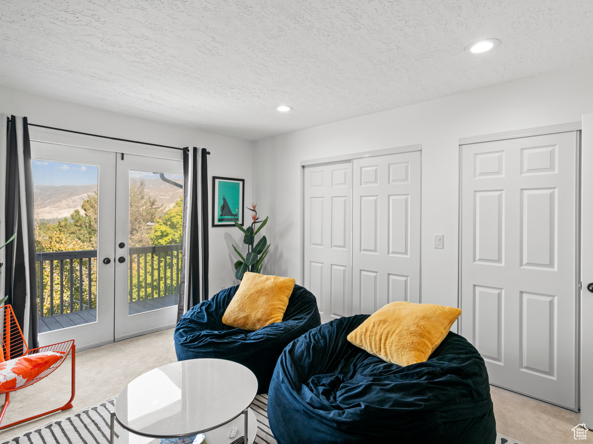 Bedroom with french doors, light carpet, access to exterior, and a textured ceiling