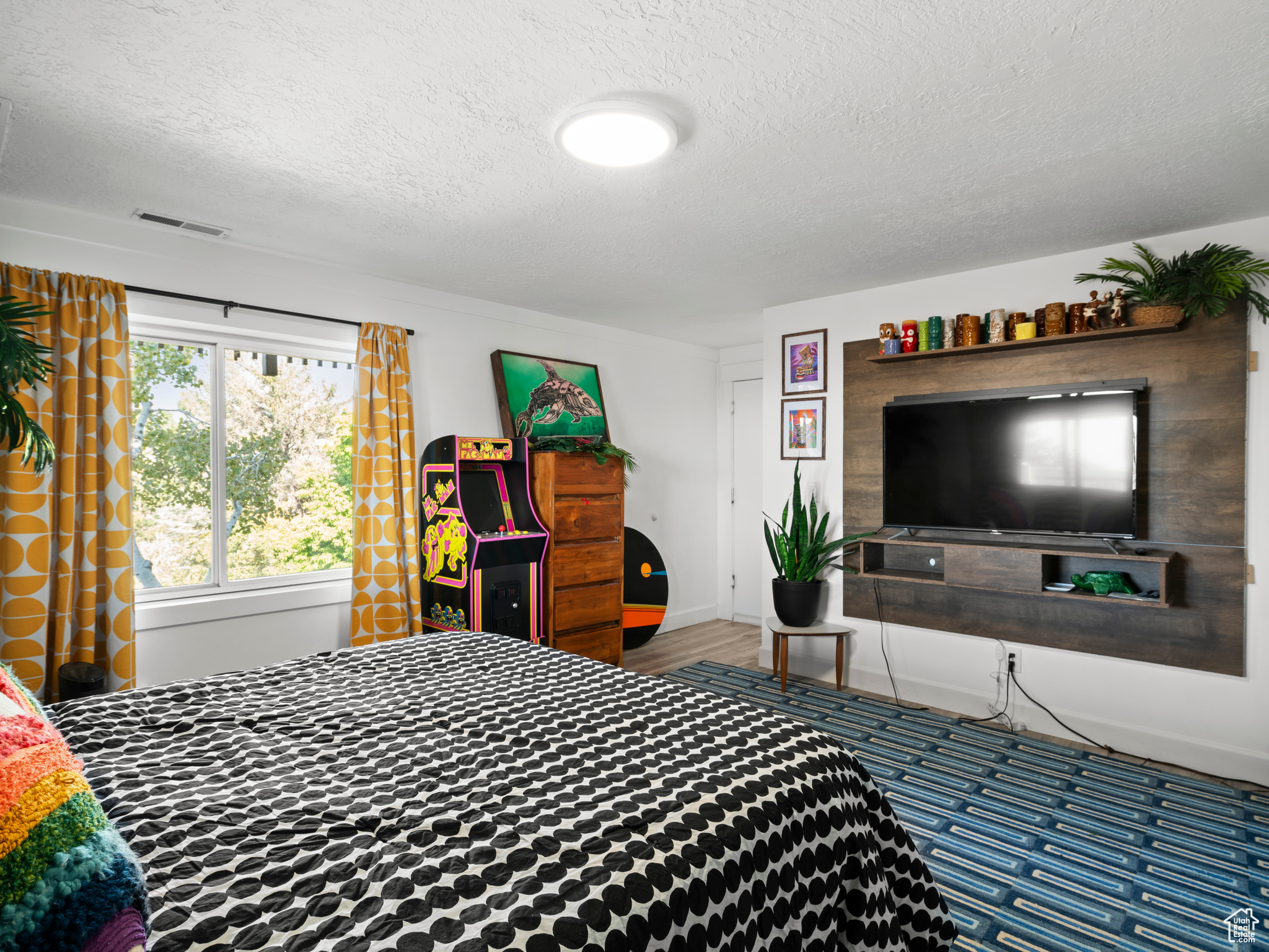 Family room set up as bedroom with a textured ceiling and hardwood / wood-style floors